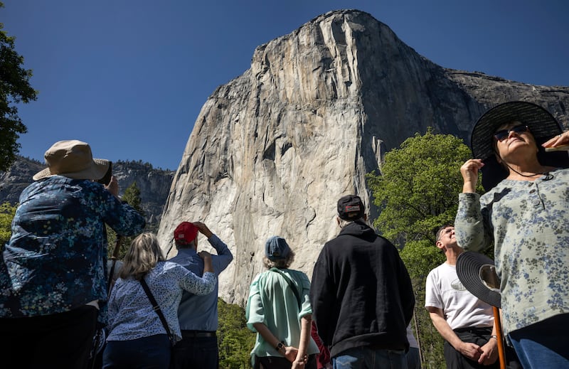 Visitors look up at El Capitan from El Capitan Meadow in Yosemite National Park, Calif.