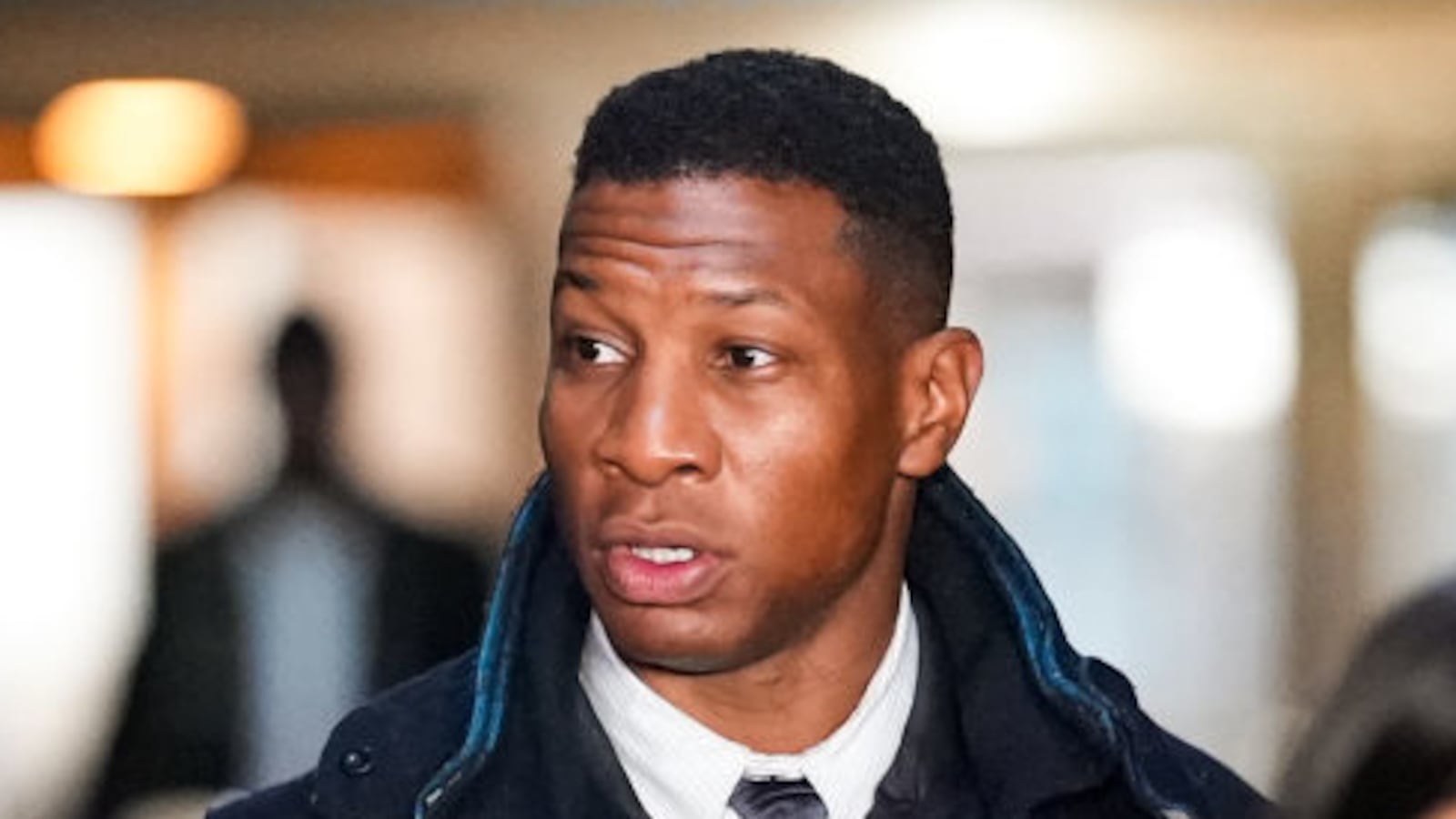 A photo of Jonathan Majors outside court