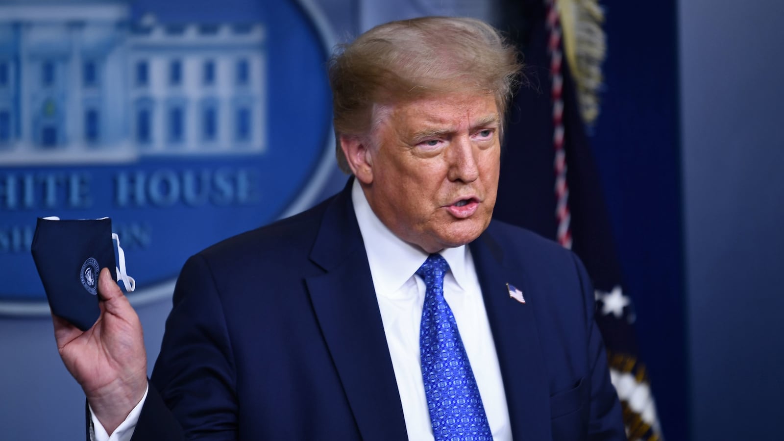 Donald Trump holds a face mask during the COVID pandemic.
