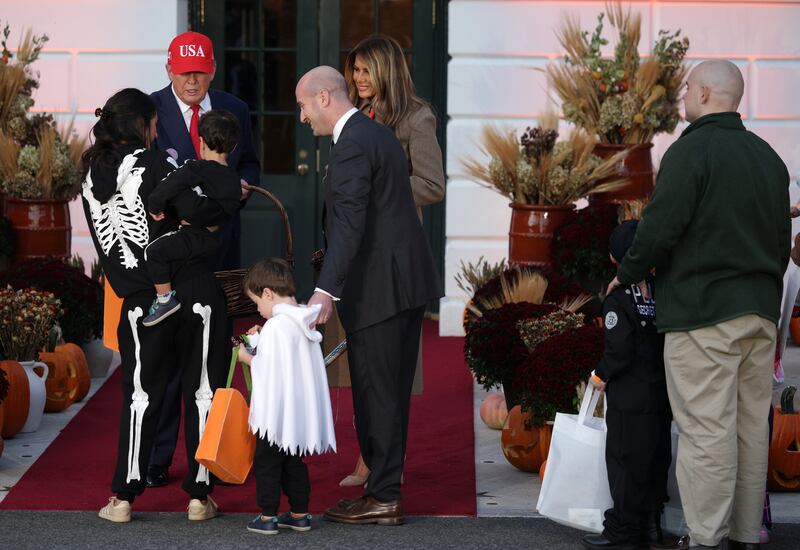 WASHINGTON, DC - OCTOBER 30: U.S. President Donald Trump talks with White House Deputy Chief of Staff Stephen Miller and his family as Trump and first lady Melania Trump handout candy to children during the annual Halloween at the White House event on the South Lawn of the White House on October 30, 2025 in Washington, DC. The President and first lady welcomed military, law enforcement, and foster and adoptive families, as well as administration officials and their children, to the annual trick-or-treat celebration on the White House grounds.
