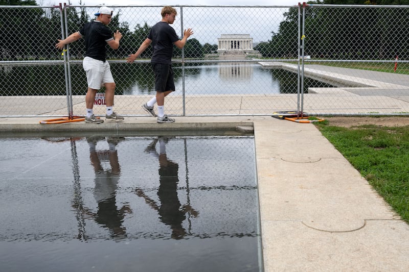 People carefully walk between the fencing surrounding the Lincoln Memorial Reflecting Pool and the World War II Memorial on the National Mall in Washington, DC on July 8, 2026. (Photo by Kent Nishimura / AFP via Getty Images)