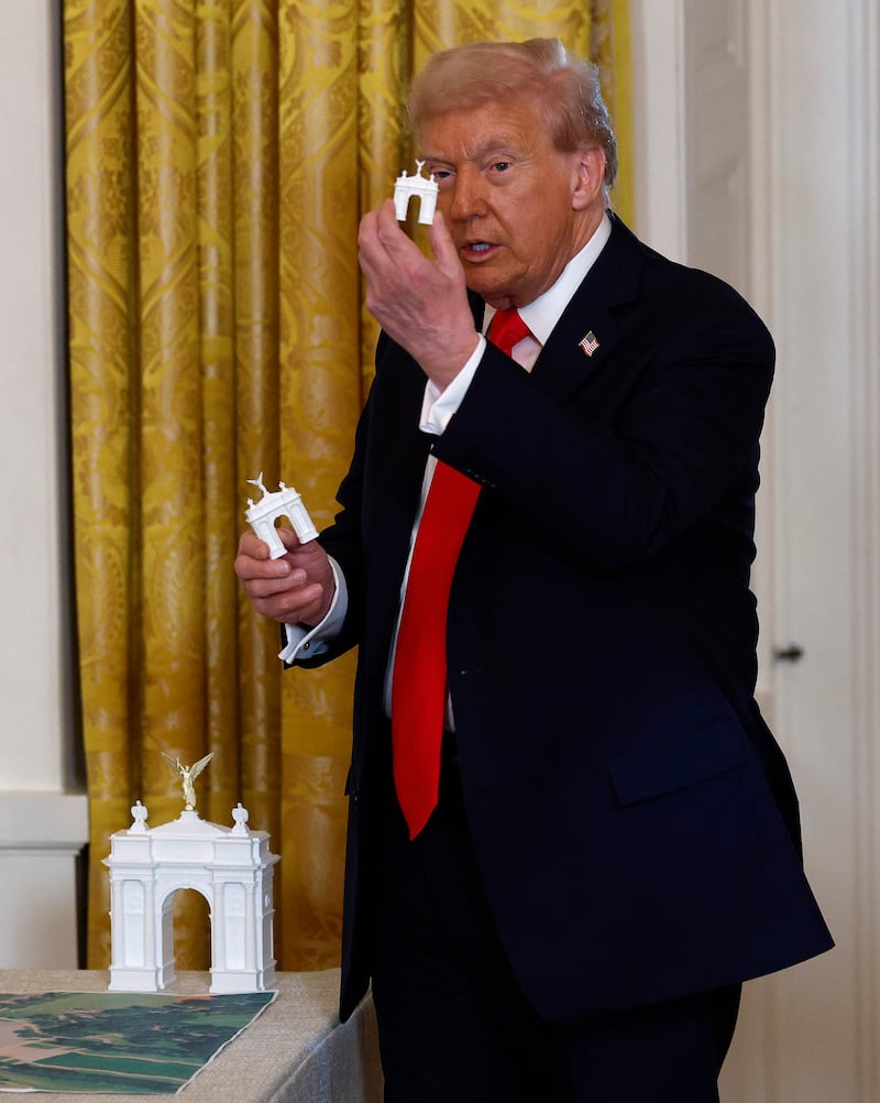 President Donald Trump holds models of an arch as he delivers remarks during a ballroom fundraising dinner in the East Room of the White House on October 15, 2025 in Washington, DC.