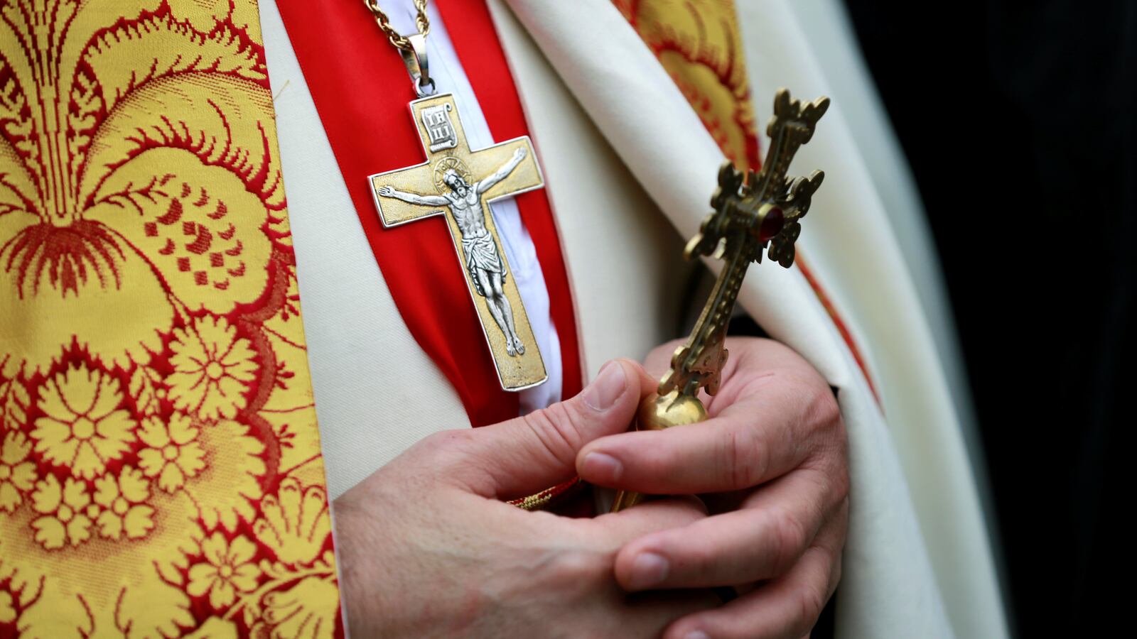 A priest holds a cross.