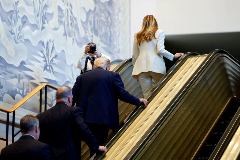 President Donald Trump and first lady Melania Trump walking up the escalator.