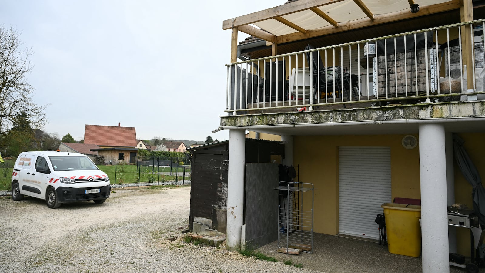 A photo shows a residential building, with the involved suspects' terrace at the first level (R), and parking area at the location where a boy was discovered naked and malnourished on a pile of rubbish in a van where he had been kept locked up, in Hagenbach, eastern France, on April 10, 2026. Gendarmes discovered the child on April 6, 2026, after being alerted by a local resident who had heard "the sounds of a child" coming from a van parked in a resident's courtyard. The nine-year-old endured a nightmare for over a year in the small village of southern Alsace, according to the public prosecutor in Mulhouse, who announced on April 10 that the boy's father and his partner had been charged. (Photo by SEBASTIEN BOZON / AFP via Getty Images)