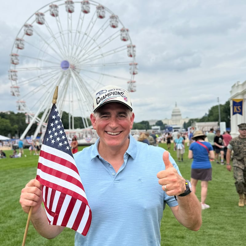 Rep. Michael Baumgartner standing on the National Mall lawn in front of the Ferris wheel, with only a handful of people visible behind him.