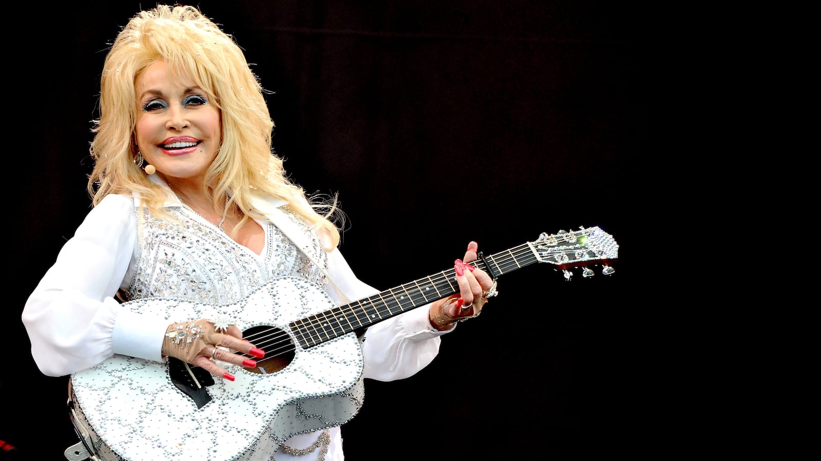 Dolly Parton plays a bedazzled guitar.