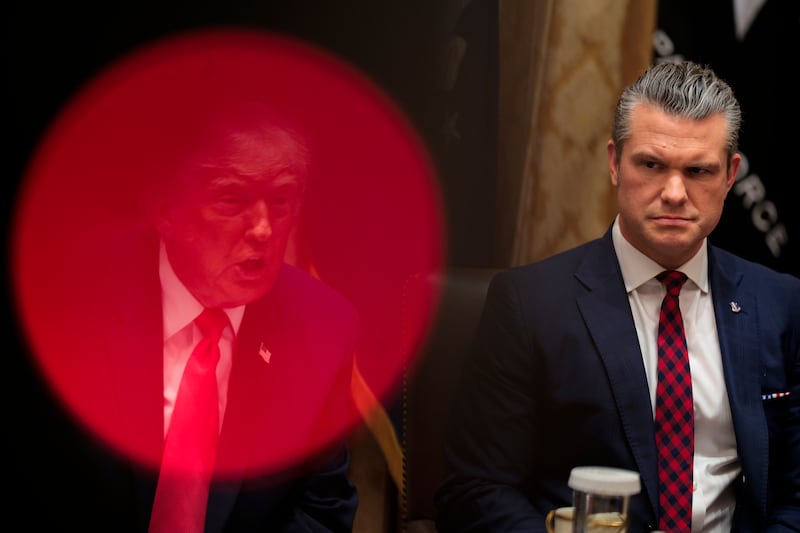 U.S. President Donald Trump (L) speaks as U.S. Secretary of War Pete Hegseth looks on.