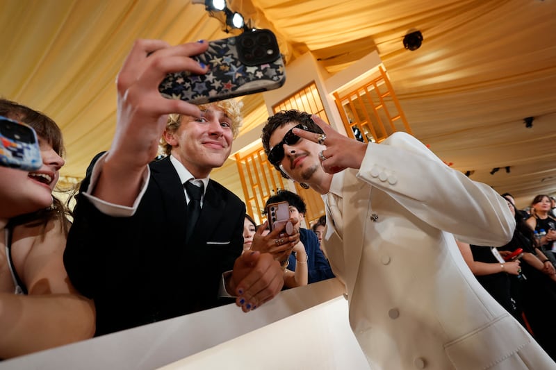 Timothee Chalamet poses with a fan on the red carpet during the Oscars arrivals at the 98th Academy Awards in Hollywood, Los Angeles, California, U.S., March 15, 2026.
