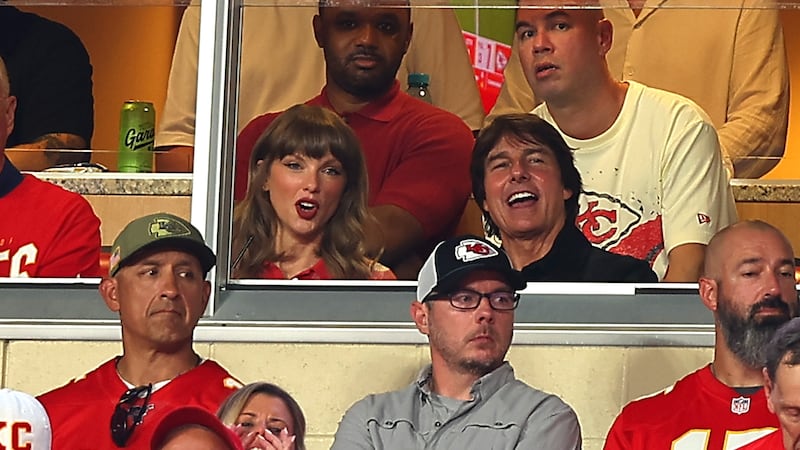 Singer Taylor Swift and actor Tom Cruise are pictured sitting in a VIP suite at a Kansas City Chiefs game. They are both cheering.