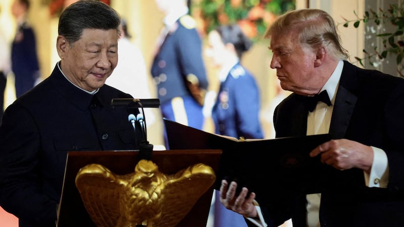 Donald Trump holds a binder next to Chinese President Xi Jinping before Xi delivers a speech at a state dinner at the White House.