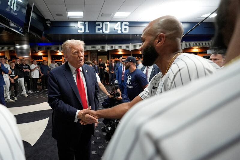 Donald Trump talks to players in the New York Yankees locker room before a baseball game.