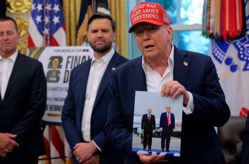 WASHINGTON, DC - AUGUST 22: U.S. President Donald Trump holds a photograph he said was given to him as a gift by Russian President Vladimir Putin in the Oval Office at the White House August 22, 2025 in Washington, DC. Trump announced the FIFA World Cup 2026 draw will take place at The Kennedy Center. (Photo by Chip Somodevilla/Getty Images)