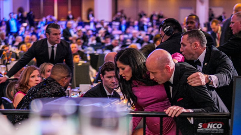 Secretary of War Pete Hegseth (L) stands as White House Deputy Chief of Staff for Policy Stephen Miller and his wife Katie Miller (C) are taken out of the ballroom by security agents during a shooting incident at the annual White House Correspondents Association Dinner at the Washington Hilton on April 25, 2026 in Washington, DC.