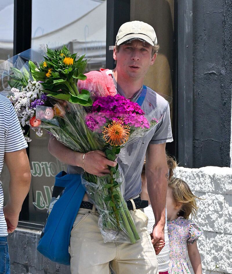 Jeremy Allen White walking outside with a bouquet of flowers