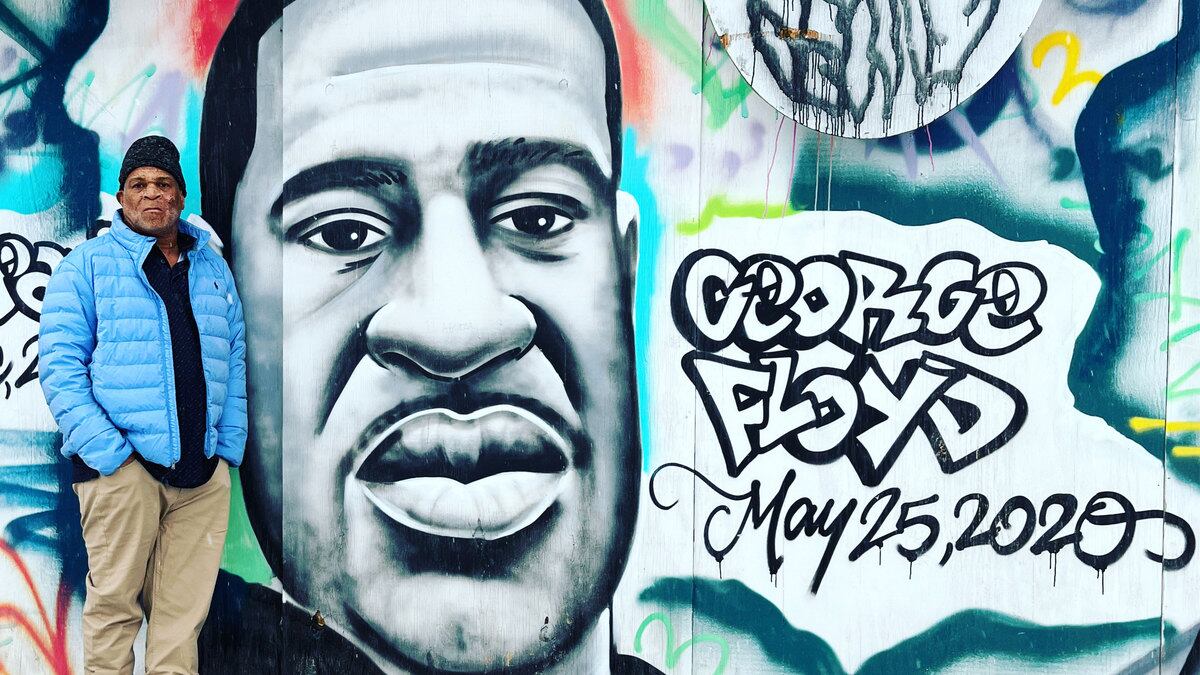 Selwyn Jones next to a mural of his nephew, George Floyd