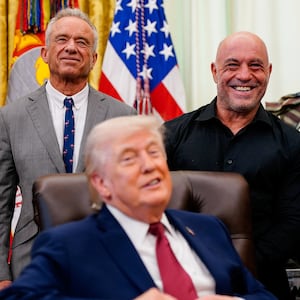 Americans for Ibogaine CEO Bryan Hubbard, podcaster Joe Rogan and U.S. Health and Human Services (HHS) Secretary Robert F. Kennedy Jr. stand behind President Donald Trump, after he signed an executive order about easing restrictions on mental health treatments, including, ibogaine, in the Oval Office of the White House in Washington, D.C., April 18, 2026. REUTERS/Nathan Howard
