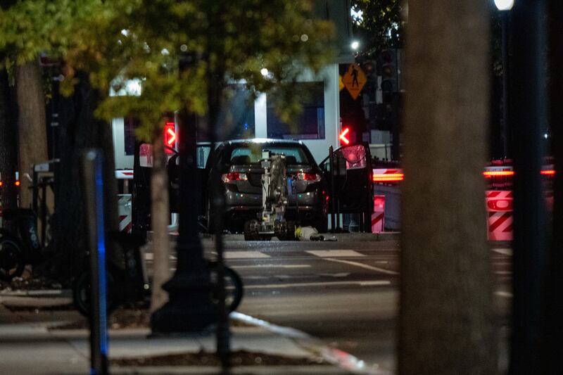 A bomb detection robot inspects a vehicle that rammed a security barricade