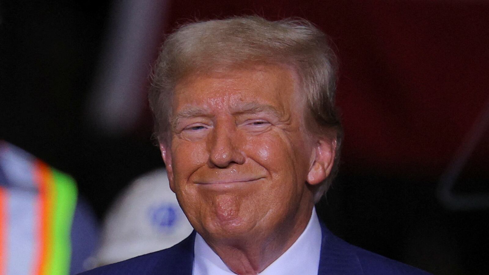 Donald Trump smiles while on stage at a campaign event.