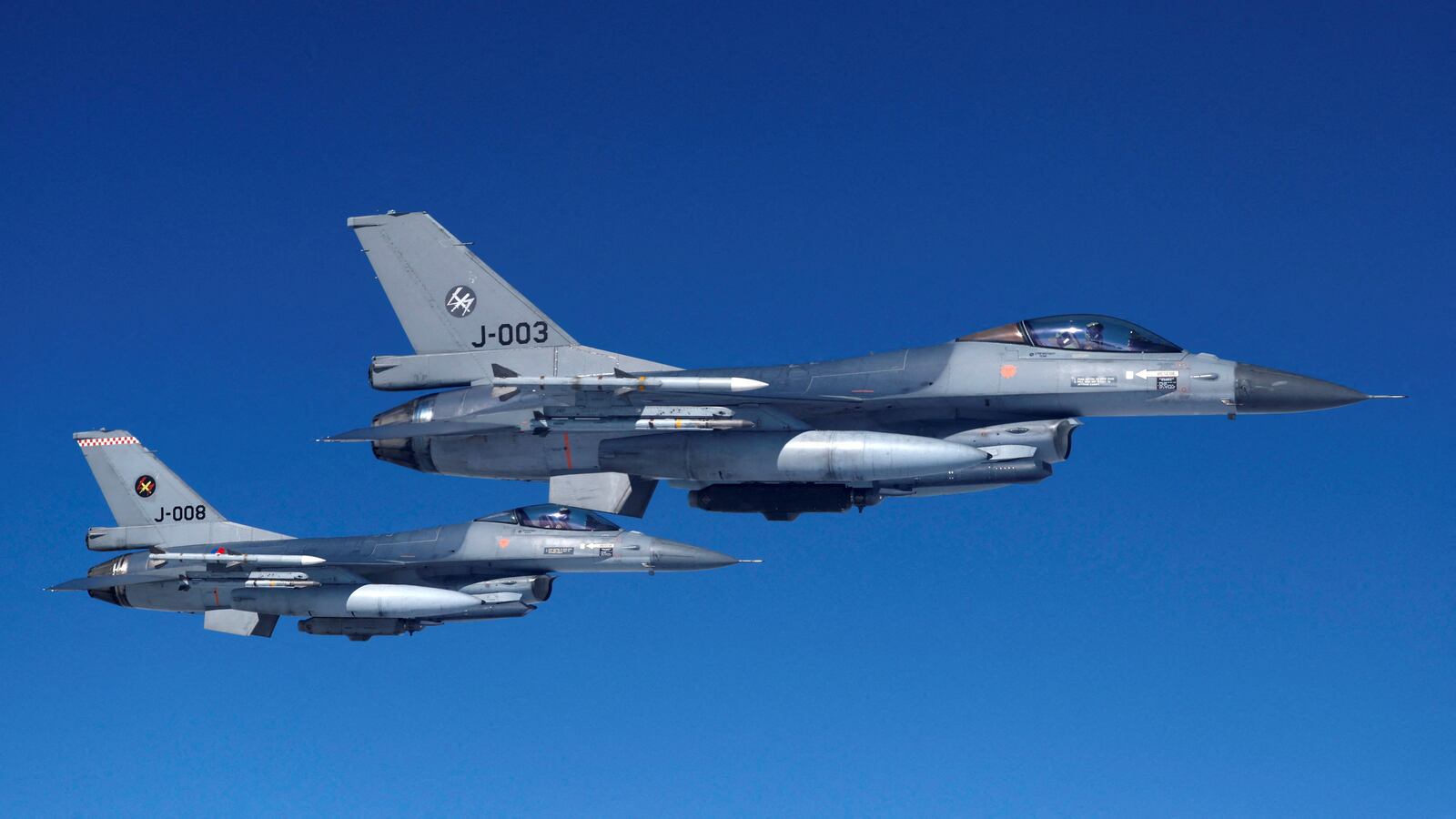 Netherlands’ Air Force F-16 fighter jets fly alongside an aircraft simulating aerial interceptions during a media day illustrating how NATO Air Policing safeguards the Allies’ airspace in the northern and northeastern region of the Alliance, July 4, 2023.