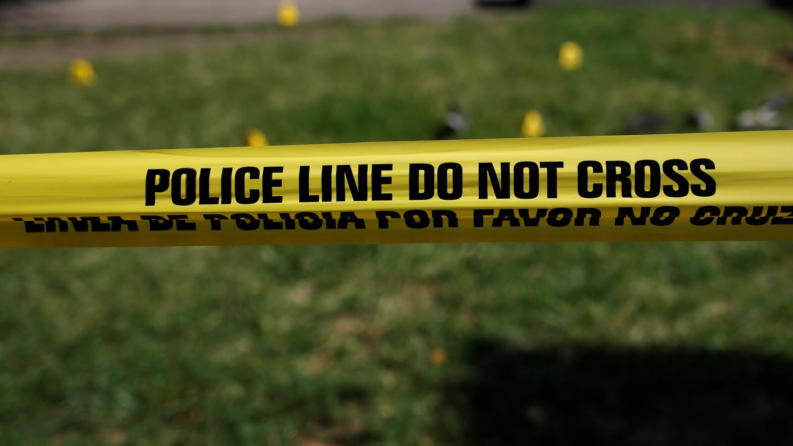 Police tape saying "POLICE LINE DO NOT CROSS" in front of grass