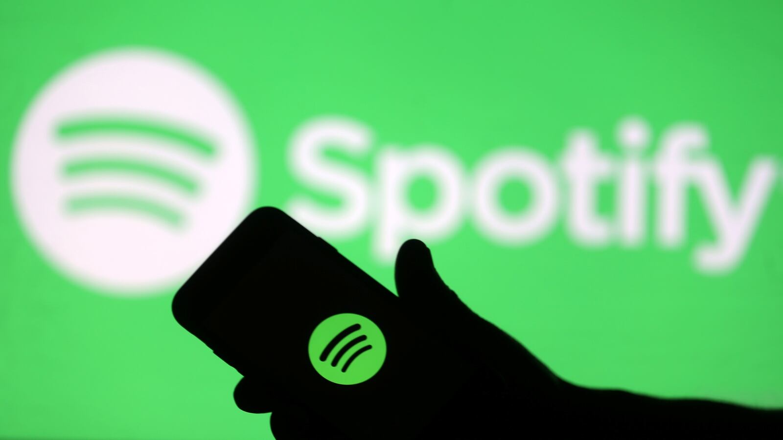 A smartphone is seen in front of a screen projection of Spotify logo, in this picture illustration taken April 1, 2018.