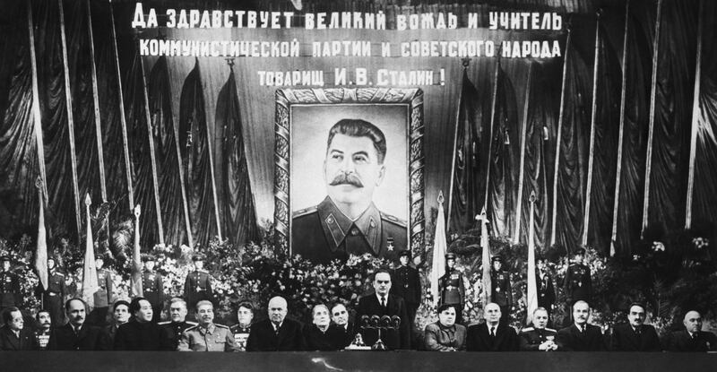 While a huge portrait of the guest of honor beams down from the rear like "Big Brother" Communist top brass pay honor to Marshall Josef Stalin on the Soviet Premier's 70th birthday.