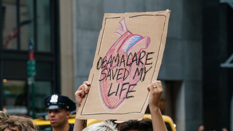 Participants hold signs while protesting the repeal and replacement of the Affordable Care Act.