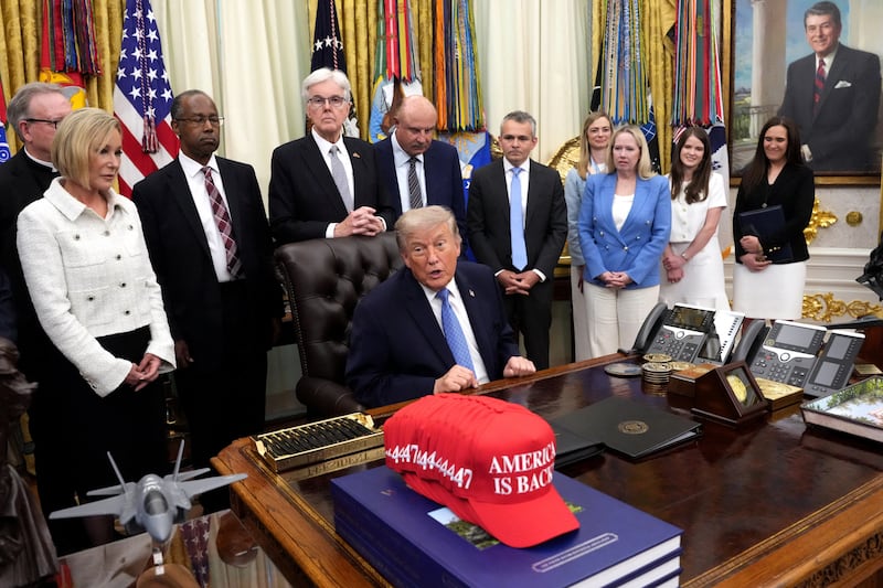 Trump receives the report from his Religious Liberty Commission on Friday as Paula White (left) looks on.
