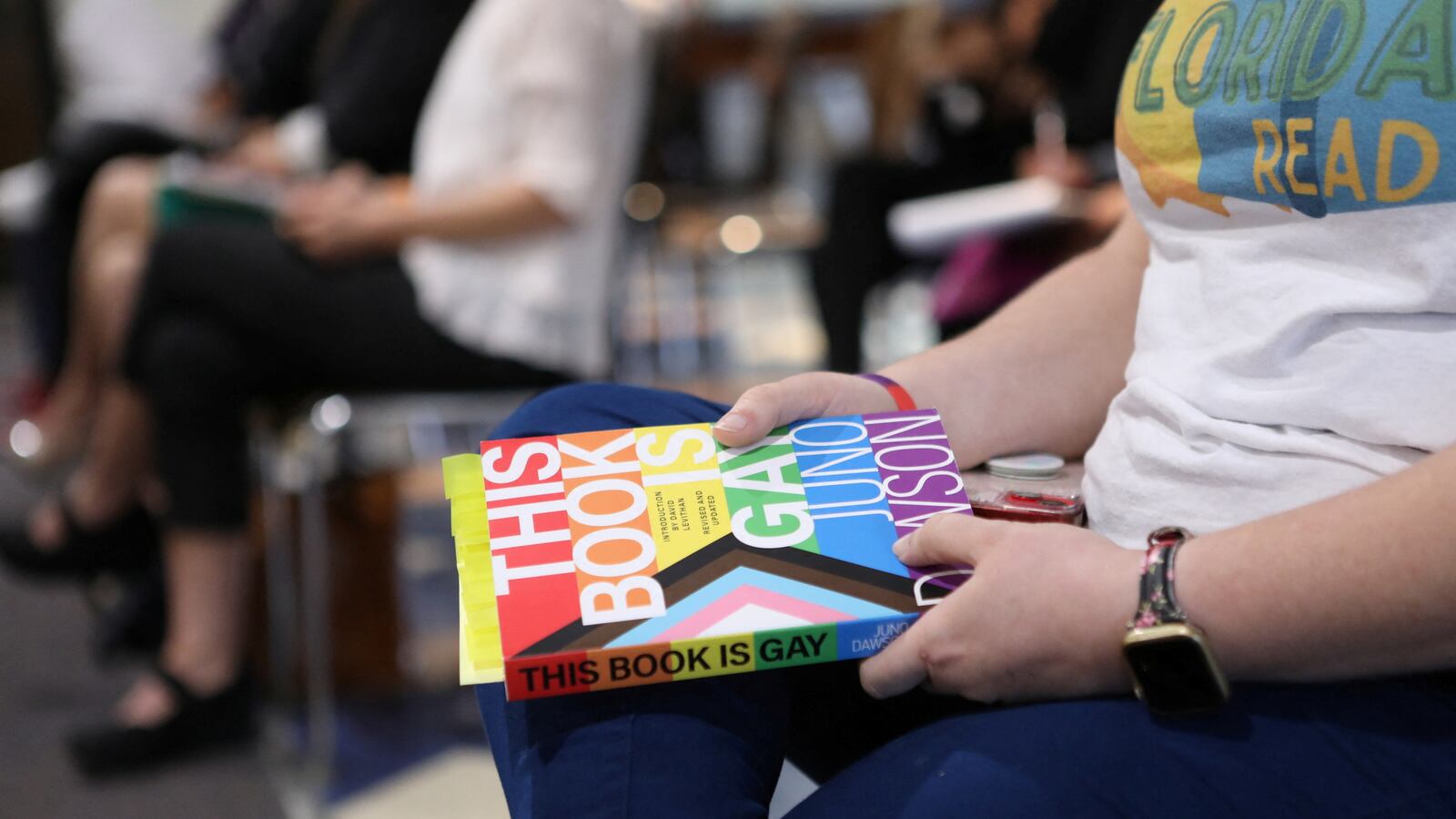 Kathleen Daniels holds a copy of \"This Book is Gay\" during public comments of those who are speaking in support or opposing the ban of a book.