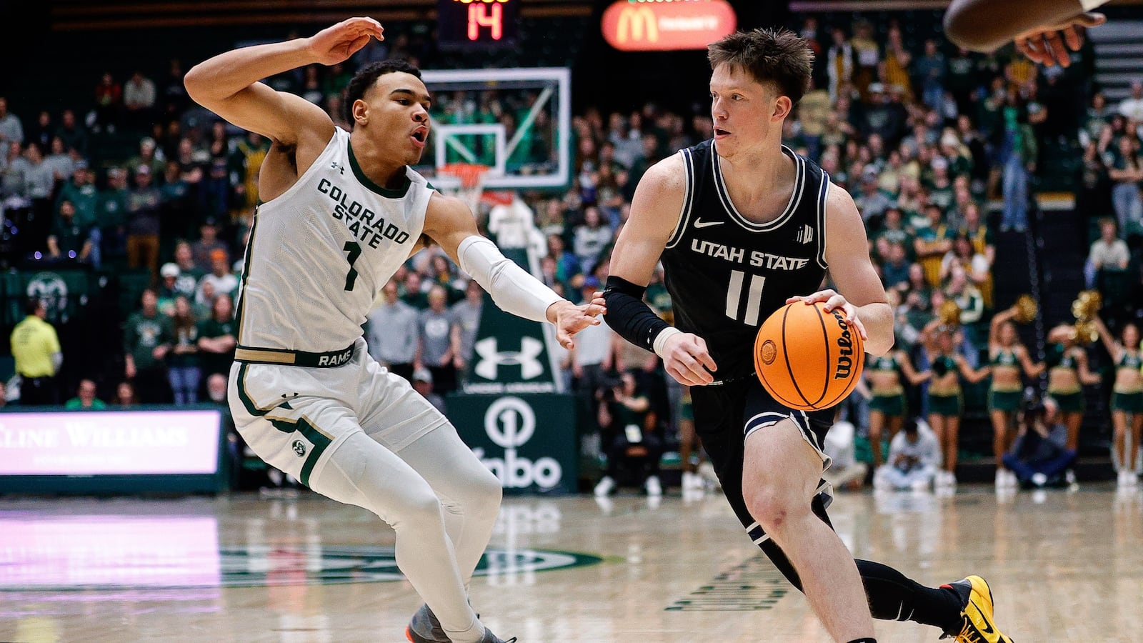 Utah State Aggies guard Max Shulga dribbles past Colorado State Rams guard John Tonje.