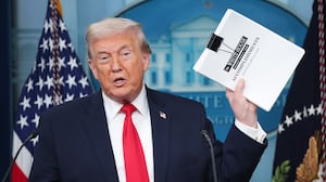 President Donald Trump displays a stack of papers labeled "The White House Accomplishments" as he arrives for a press briefing on January 20, 2026.
