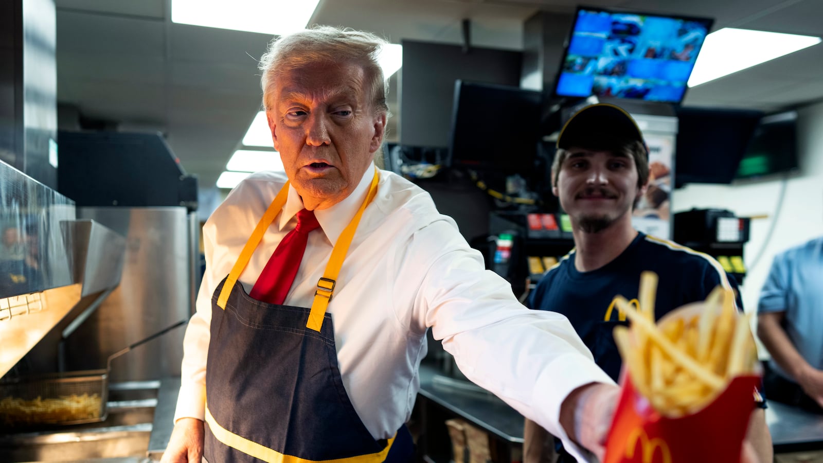 President Trump wearing a McDonald's apron hands fries to someone off camera.