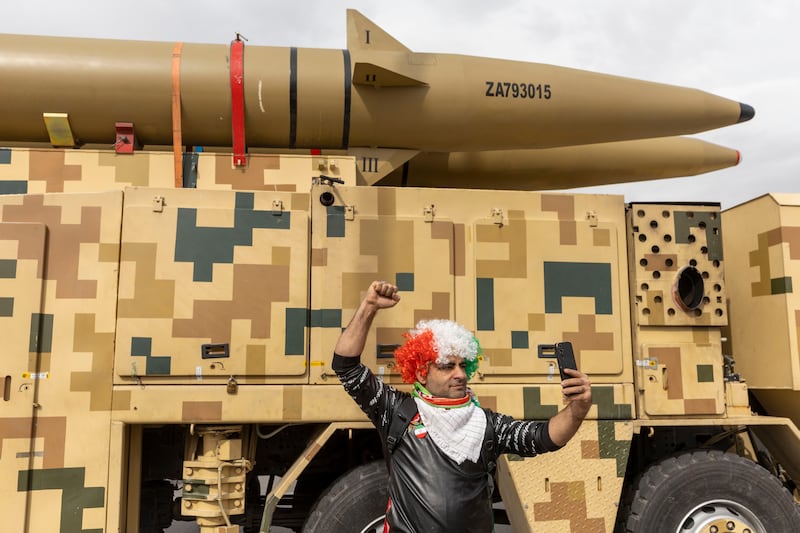 TEHRAN, IRAN - FEBRUARY 11: An Iranian participant wearing a wig takes a photo with a displayed missile produced by Iran's armed forces during commemorations to mark the anniversary of the 1979 Iranian Revolution on February 11, 2026 in Tehran, Iran. In that year, Ruhollah Khomeini led an overthrow of the Pahlavi dynasty in 1979 and established himself as Supreme Leader of the Islamic Republic of Iran. (Photo by Majid Saeedi/Getty Images)