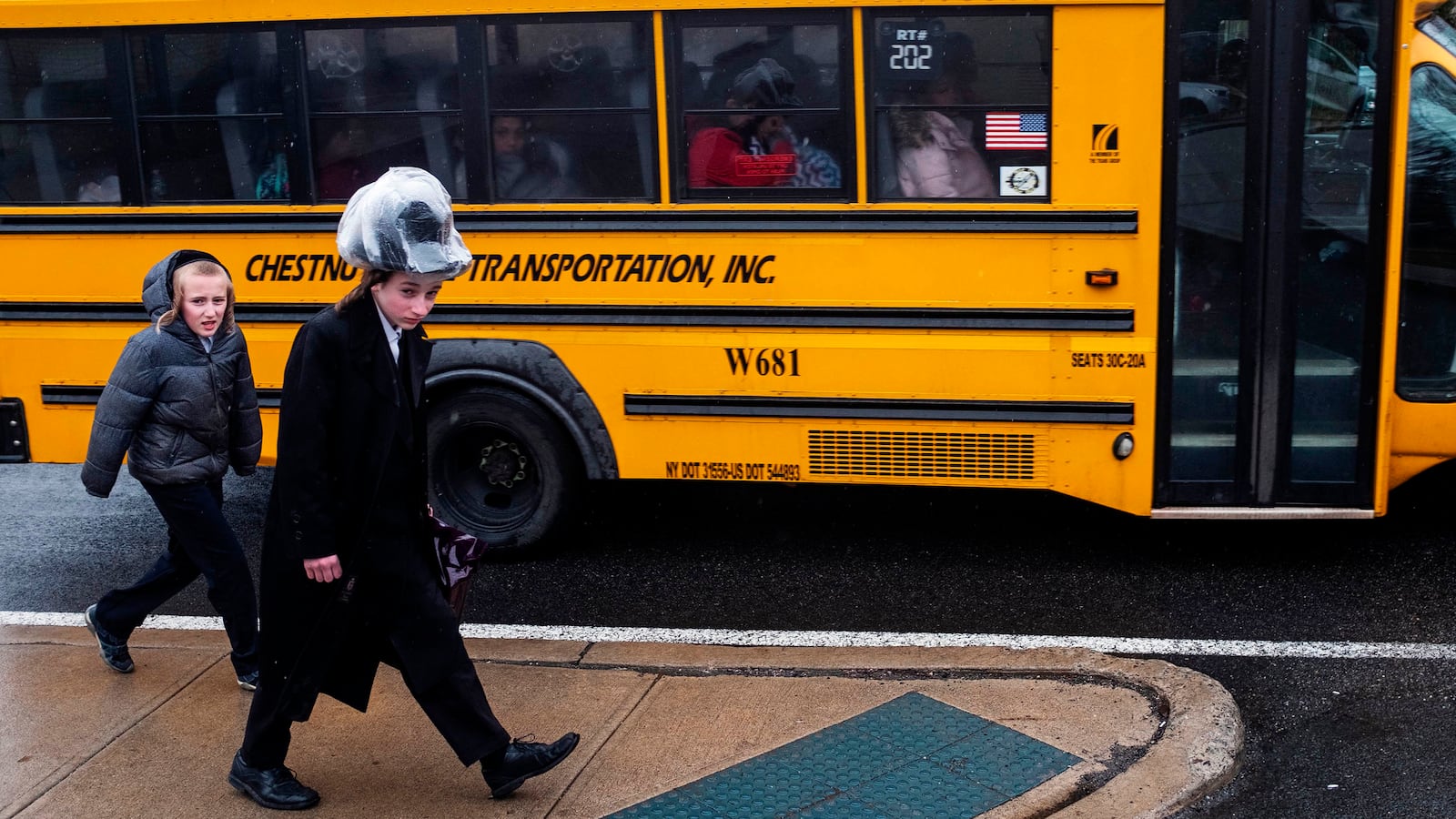 photo of two boys walking next to a school bus in a jewish neighborhood in monsey rockland county new york measles outbreak anti vax antivax rockland country de blasio forced vaccination del bigtree lawrence palevsky andrew wakefield williamsburg orthodox