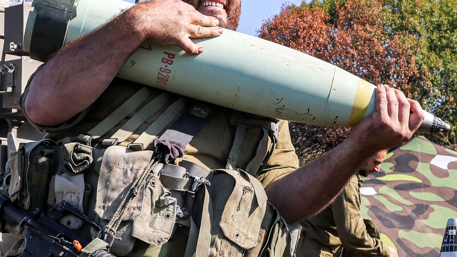 An Israeli army soldier reacts while transporting a 155mm artillery shell