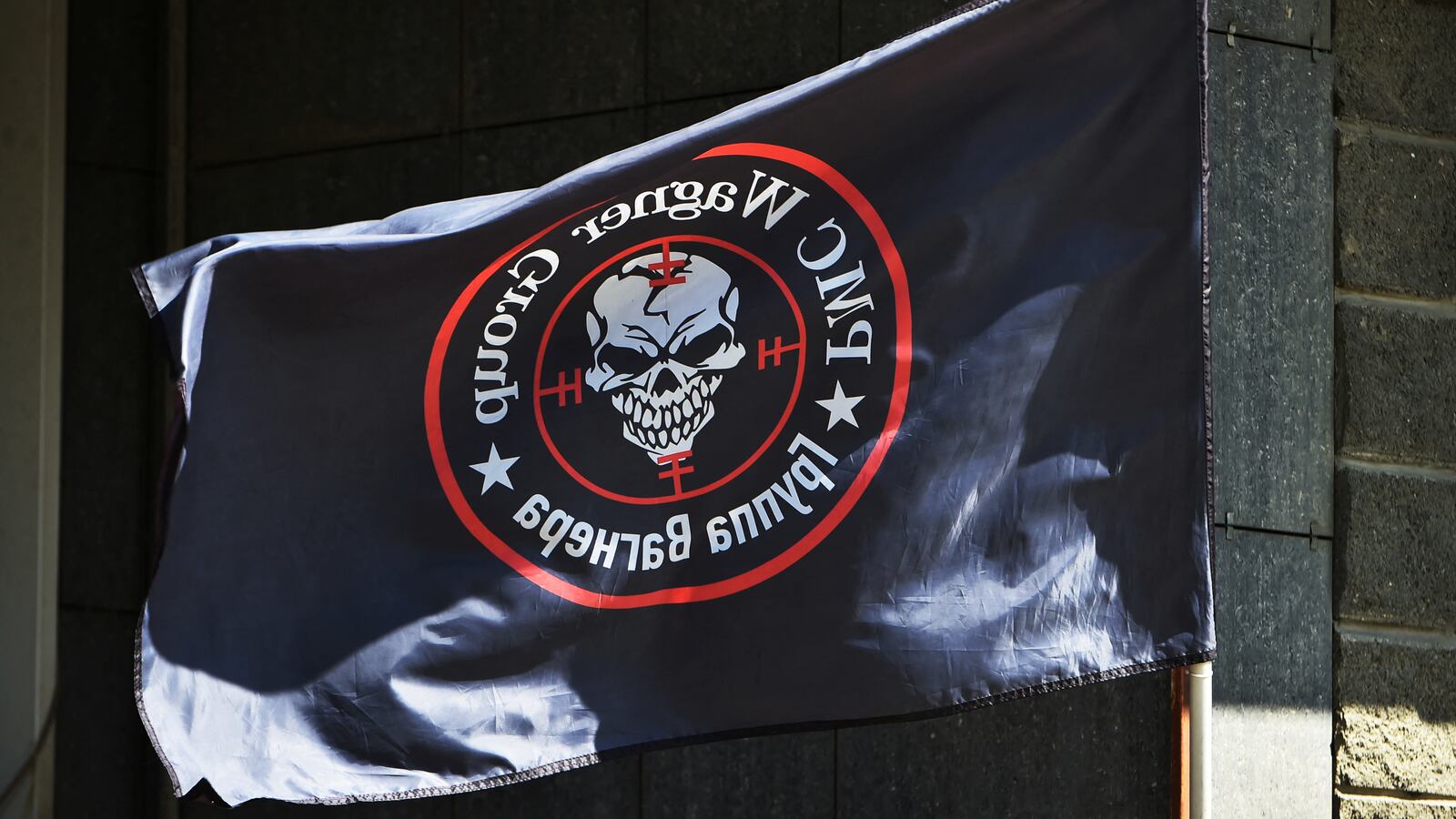 A black flag emblazoned with the PMC Wagner logo flying.