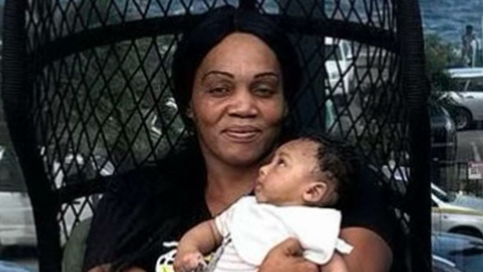 Neville Hewitt stands next to his mother, Deon Jones, who is holding his son.