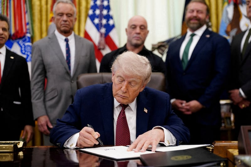FILE PHOTO: FILE PHOTO: U.S. President Donald Trump signs an executive order encouraging more research into ibogaine, next to U.S. Health and Human Services (HHS) Secretary Robert F. Kennedy Jr., Joe Rogan, and Americans for Ibogaine CEO W. Bryan Hubbard, in the Oval Office of the White House in Washington, D.C., April 18, 2026. REUTERS/Nathan Howard/File Photo/File Photo