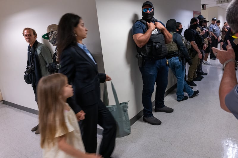 A woman and child walk past Federal agents as they patrol the halls of immigration court at the Jacob K. Javits Federal Building