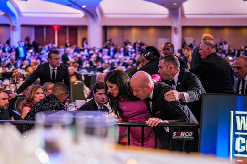 Secretary of War Pete Hegseth (L) stands as White House Deputy Chief of Staff for Policy Stephen Miller and his wife Katie Miller (C) are taken out of the ballroom by security agents during a shooting incident at the annual White House Correspondents Association Dinner at the Washington Hilton on April 25, 2026 in Washington, DC.