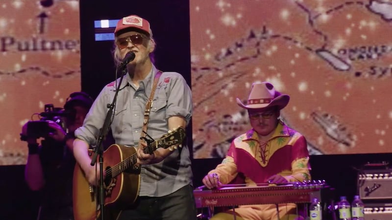 Greg Keelor of Blue Rodeo sings in front of a map of Lake Ontario.