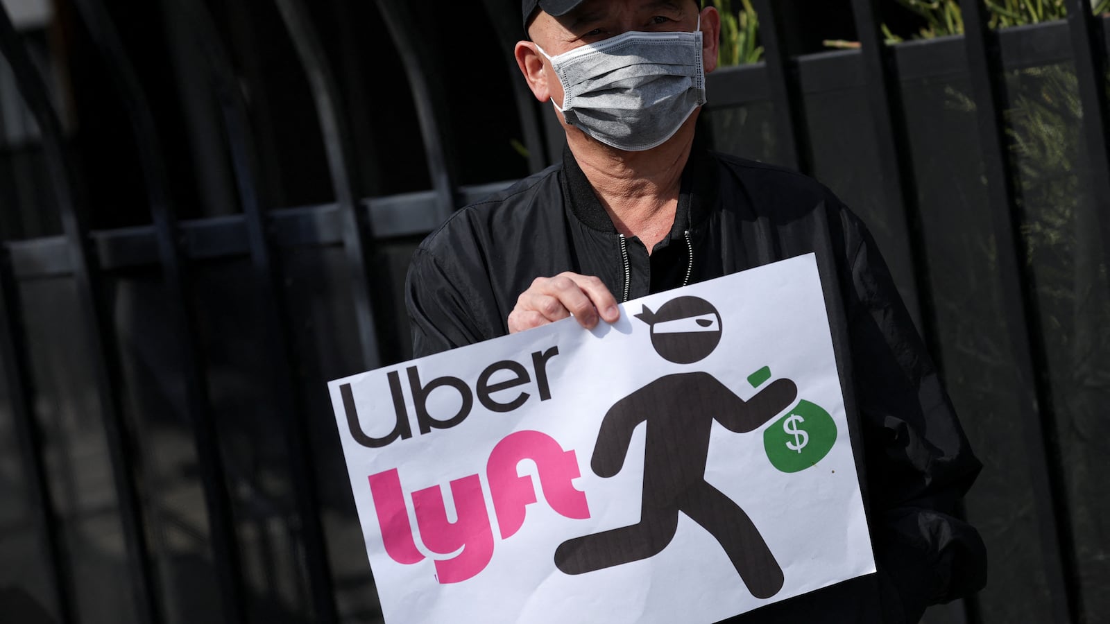 A person holds a placard criticizing Uber and Lyft.