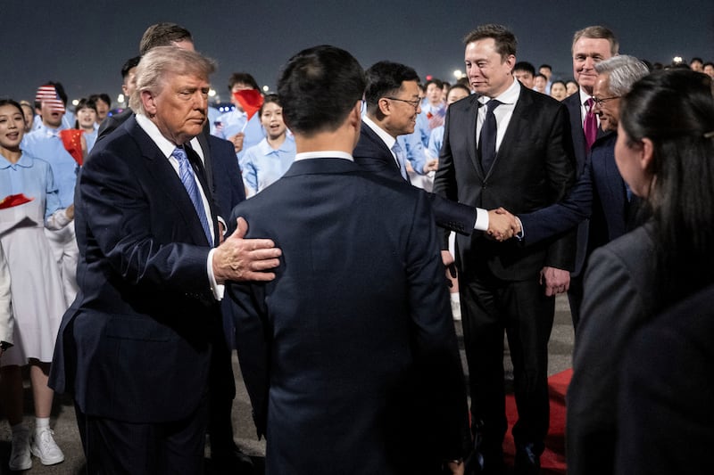TOPSHOT - US President Donald J. Trump watches as members of his delegation, including Tesla and SpaceX's CEO Elon Musk and Nvidia President and CEO Jensen Huang, are greeted by China's Vice President Han Zheng and others as they arrive at the Beijing Capital International Airport on May 13, 2026. (Photo by Brendan SMIALOWSKI / AFP via Getty Images)