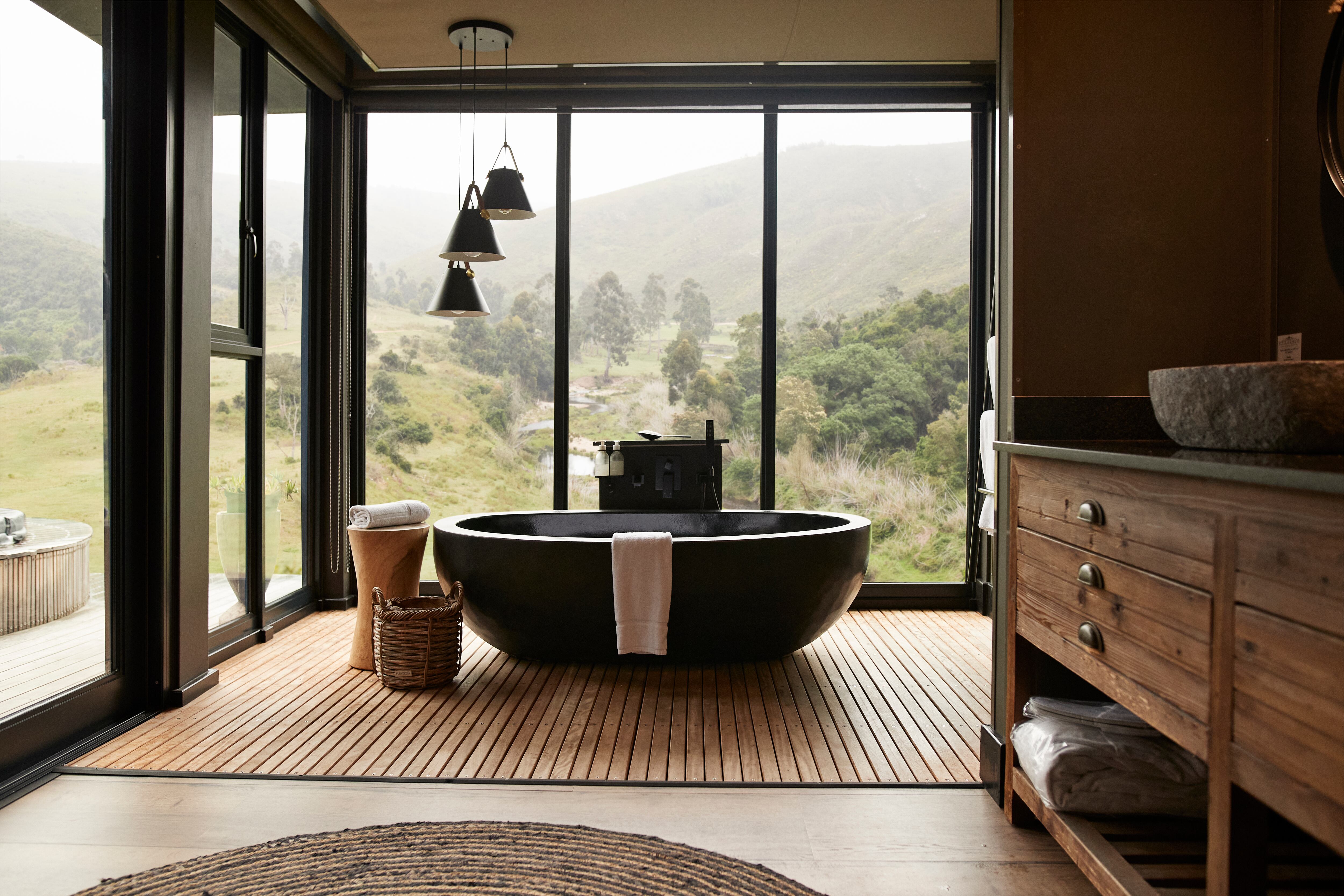 Pendant light hanging over bathtub in bathroom with large window of luxury rental vacation villa