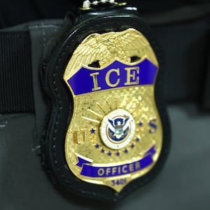 The badge of an  Immigration and Customs Enforcement (ICE) agent is seen as they patrol the halls of immigration court at the Jacob K. Javits Federal Building on June 09, 2025 in New York City.