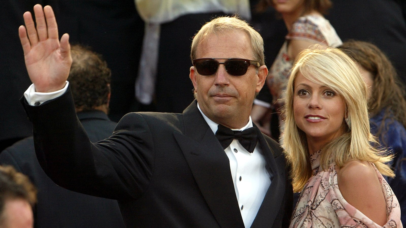 US director and actor Kevin Costner (C) waves to the crowd with his companion Cristine Baumgartner (R) during red-carpet arrivals at the 56th International Film Festival in Cannes, May 15, 2003.