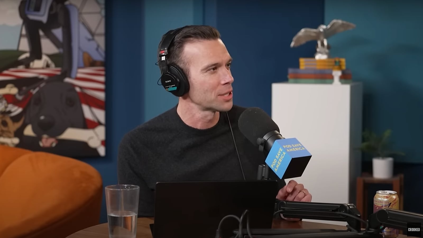 Pod Save America host Jon Favreau speaks into a microphone.