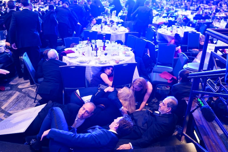 Attendees hide under tables after an  incident at the annual White House Correspondents Association Dinner April 25, 2026 in Washington, DC. According to reports, President Donald Trump, along with other government officials, were evacuated from the Washington Hilton after what sounded like gun fire.