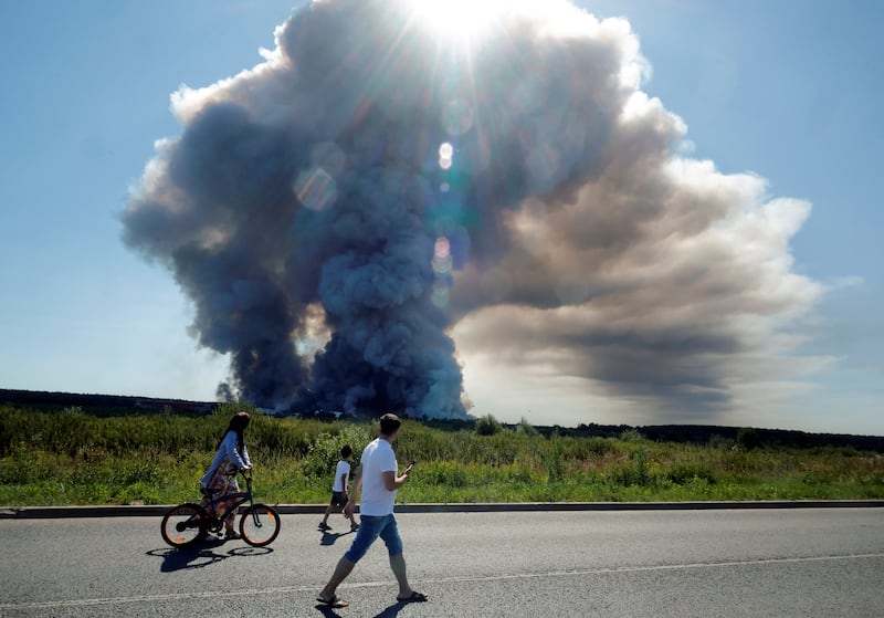 TOPSHOT - Local residents walk past the smoke of a fire at the Russian e-commerce firm Wildberries' logistics complexes in the town of Elektrostal outside Moscow on July 18, 2026. A Ukrainian drone attack on two logistics centres in Russia killed eight people and injured 24, officials said on July 18, 2026, when the Moscow region reported a new wave of drone strikes. Russian e-commerce firm Wildberries said its logistics complexes in Kotovsk and Elektrostal, in the Tambov and Moscow regions respectively, came under attack. One person was killed and 37 were injured at the Elektrostal warehouse, according to the region's governor, Andrei Vorobyov. (Photo by TATYANA MAKEYEVA / AFP via Getty Images)